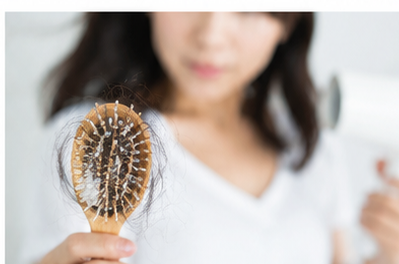 ブラシについた抜け毛を確認する女性