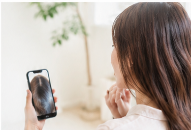 写真や鏡で頭頂部やつむじを確認する女性